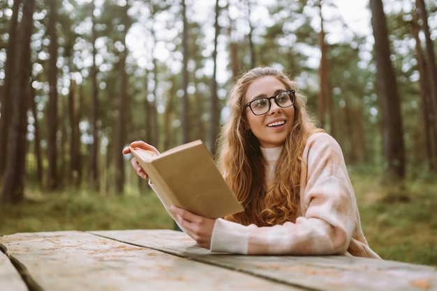 Mulher elegante lendo um livro no parque de outono