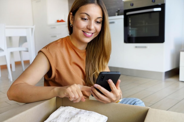 Foto mulher elegante proprietária de uma pequena empresa usando um aplicativo de smartphone para vender roupas on-line de casa