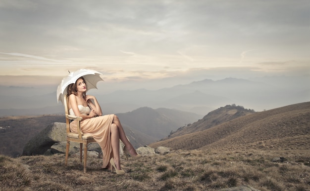 Mulher elegante, sentado em um lugar montanhoso