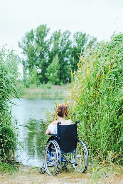 Mulher em cadeira de rodas, aproveitando o tempo olhando para o lago