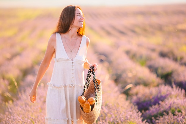 Mulher em campo de flores de lavanda com vestido branco e chapéu