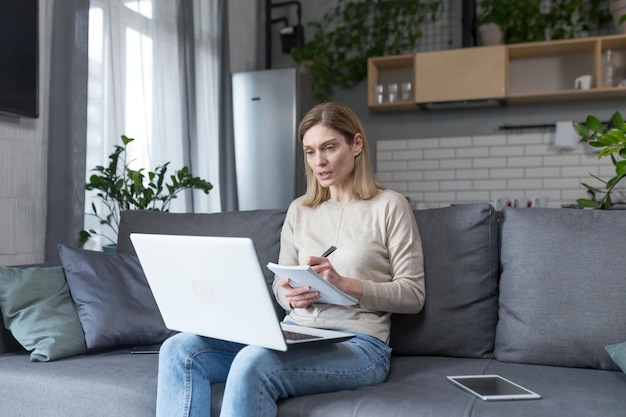 Mulher em casa estudando online usa laptop sentado no sofá em casa