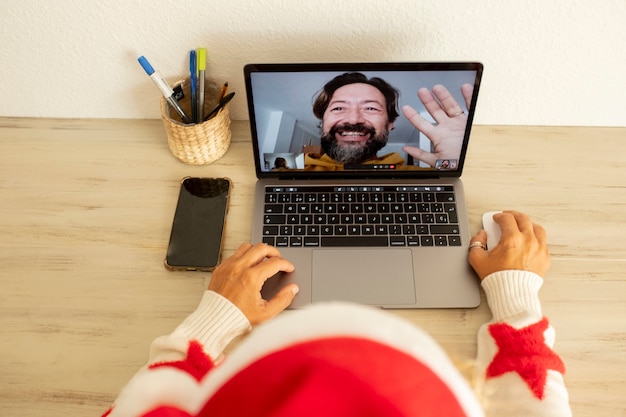 Mulher em casa no feriado de natal, chamando o homem usando o computador portátil na comunicação de videochamada online. pessoas e tecnologia de comunicação na festiva temporada de inverno