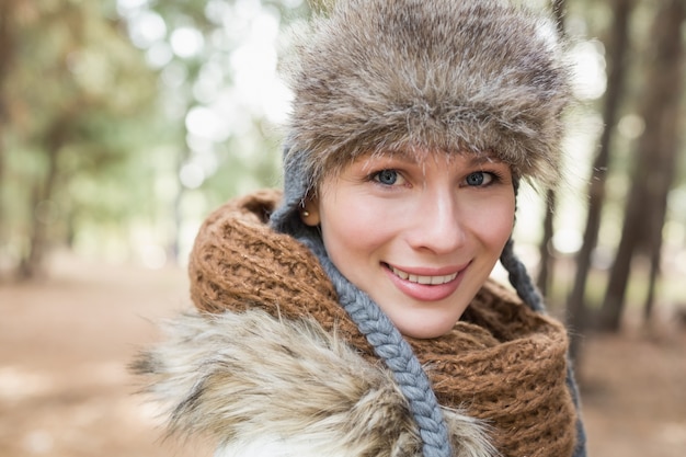 Mulher em chapéu de pele com lenço de lã na floresta