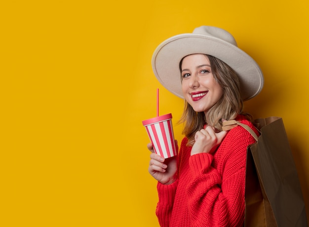 Mulher, em, chapéu, e, camisola vermelha, com, bebida, e, bolsa para compras