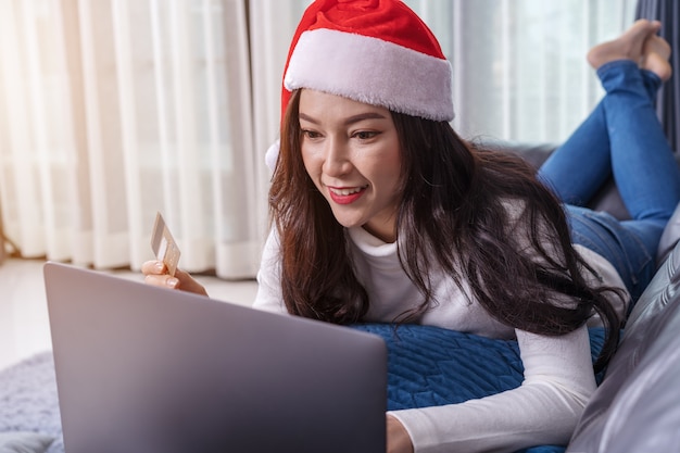 Mulher, em, chapéu santa, comprando online, para, presente natal, com, laptop, em, sala de estar