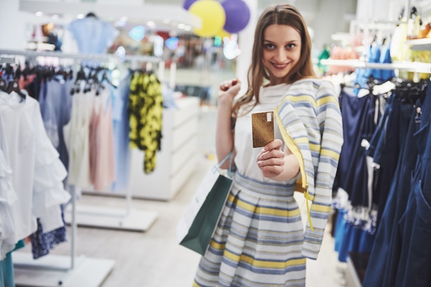 Foto mulher em compras. mulher feliz com sacos de compras e cartão de crédito, desfrutando de compras. consumismo, compras, conceito de estilo de vida