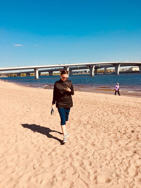 Foto mulher em comprimento na praia contra o céu