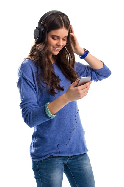 Mulher em fones de ouvido está sorrindo. Menina de camisola com telefone. As frequências graves são impressionantes. Gadgets de alta qualidade.