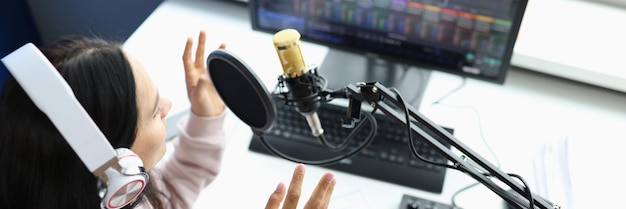 Mulher em fones de ouvido na frente do microfone transmite estúdio de gravação de rádio ou streamer