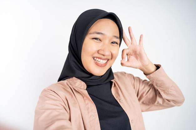 Mulher em hijab segurando um telefone inteligente para selfie