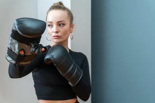 mulher em luvas de boxe apresentou uma palma aberta. Fundo desfocado.