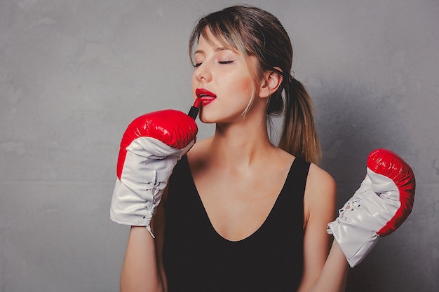 Mulher em luvas de boxe com batom vermelho nas mãos