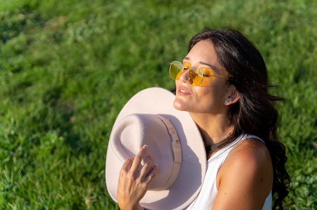 Mulher em óculos de sol, aproveitando o sol e o calor enquanto está sentado na grama