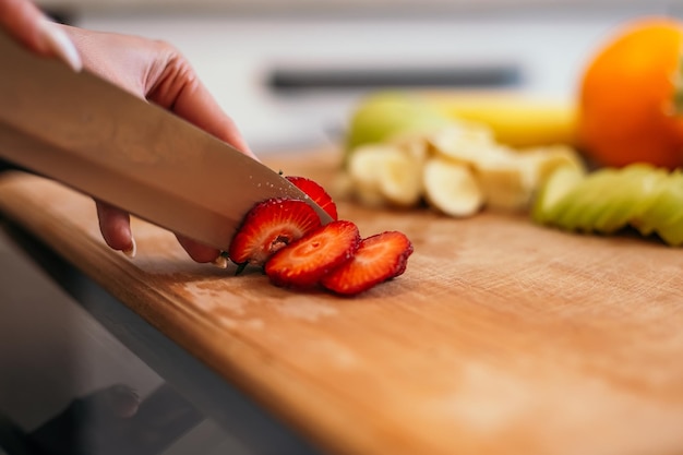 Mulher em pé na cozinha cortando salada com alimentos saudáveis