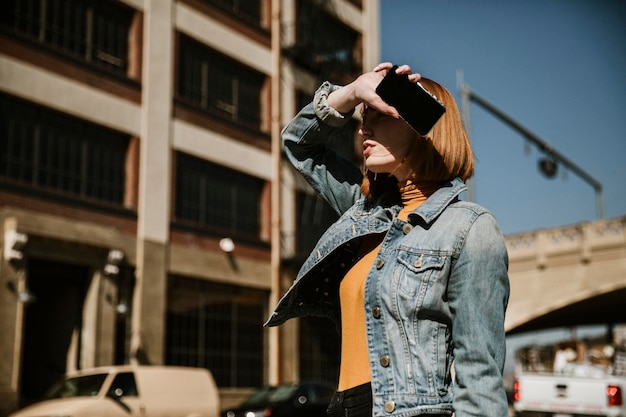 Mulher em pé na rua com seu telefone