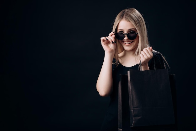 Foto mulher em pé sobre fundo preto com sacolas de compras