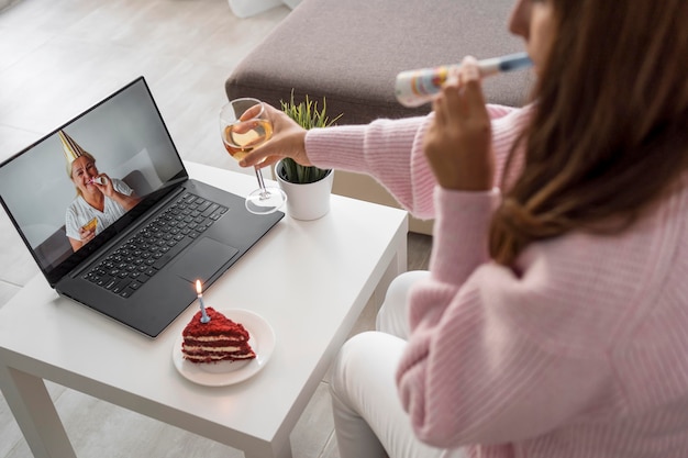 Mulher em quarentena comemorando aniversário com amigos no laptop e bebendo