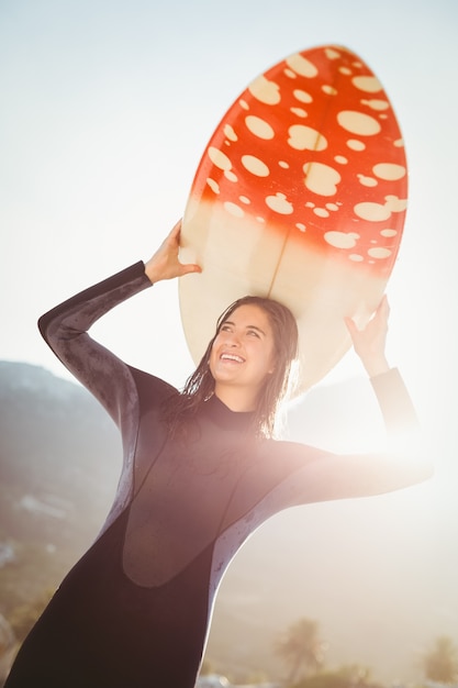 Foto mulher em roupa de mergulho com prancha de surf em um dia ensolarado
