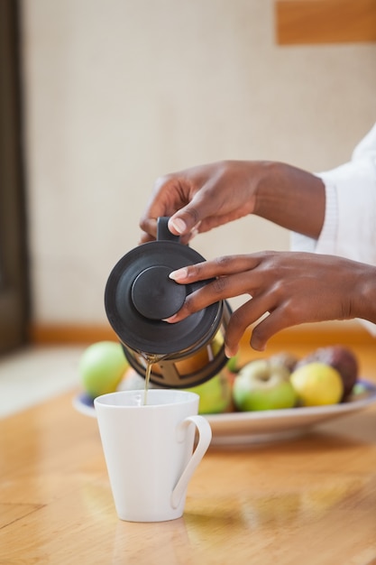 Foto mulher em roupão derramando café