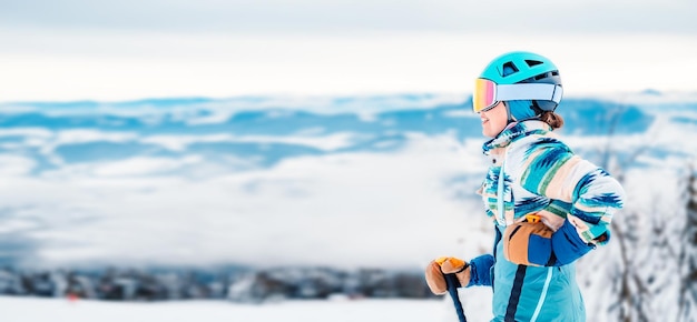 Foto mulher em roupas de esqui com capacete e googles de esqui na cabeça com bastões de esqui clima de inverno nas encostas no topo de uma montanha e apreciando a vista esquiador alpino esporte de inverno
