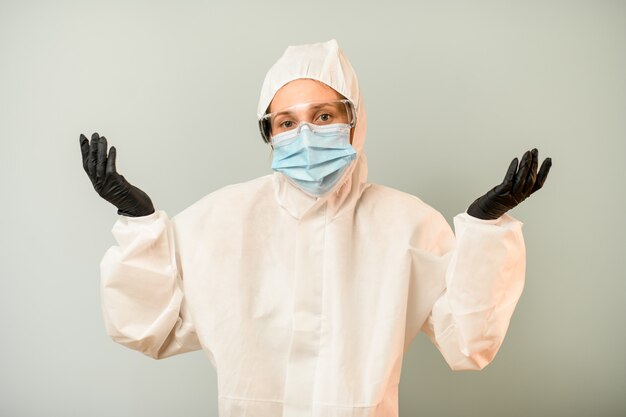 Mulher em roupas de proteção fica abrindo os braços para o lado.