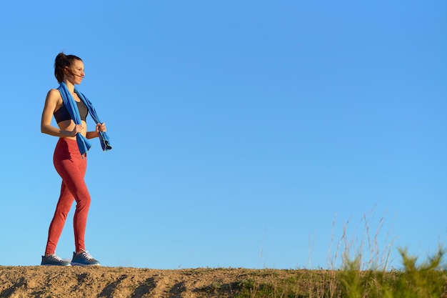 Mulher em roupas esportivas andando com toalha pela vista lateral do campo com espaço para cópia