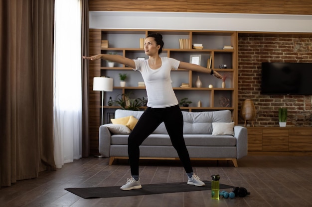 Mulher em roupas esportivas praticando ioga em casa