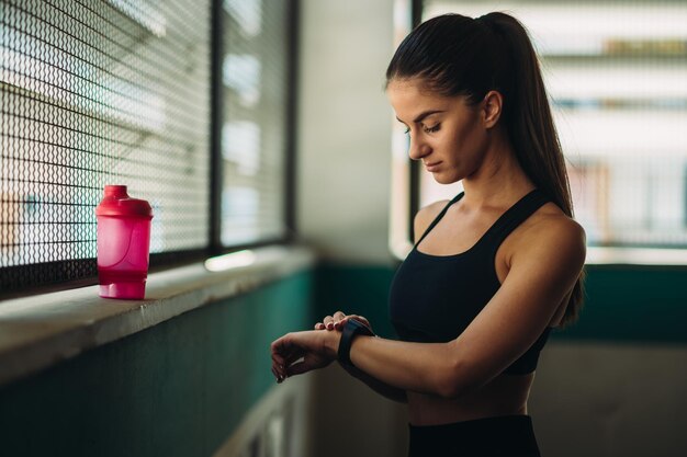 Mulher em roupas esportivas verifica fitness e rastreamento de saúde em seu smartwatch após o treino