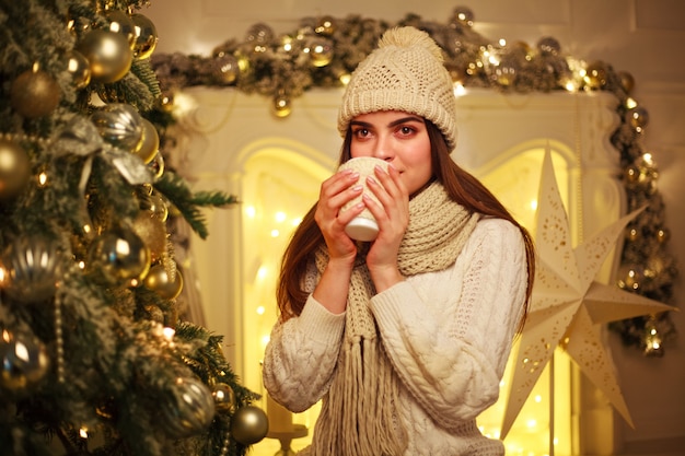 Mulher em roupas quentes, bebendo café em casa na decoração de ano novo