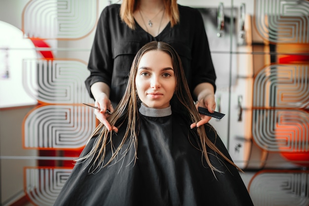 Foto mulher em salão de cabeleireiro, estilista feminina com tesoura e pente nas mãos