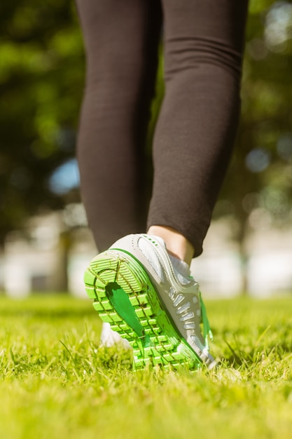 Mulher em sapatos esportivos correndo no parque