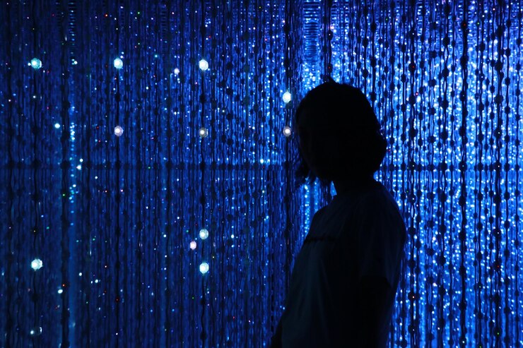 Mulher em silhueta de pé contra luzes iluminadas