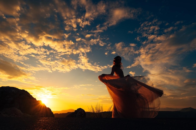 Foto mulher em silhueta de pé em terra contra o céu durante o pôr do sol