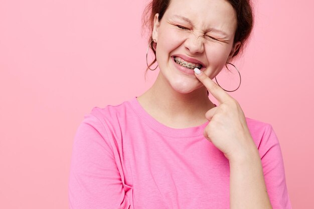 Mulher em suspensórios de camiseta rosa posando fundo rosa