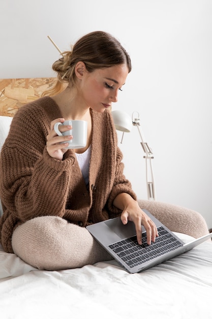 Mulher em tiro médio com laptop na cama