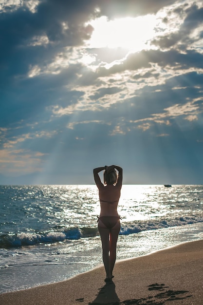 Mulher em trajes de banho caminhando na praia