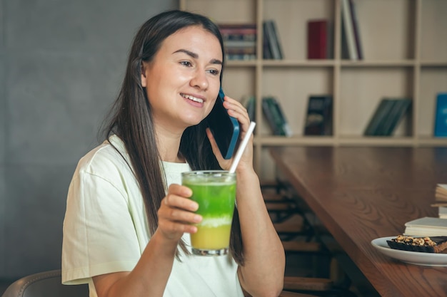 Mulher em um café com um smartphone e um copo de limonada