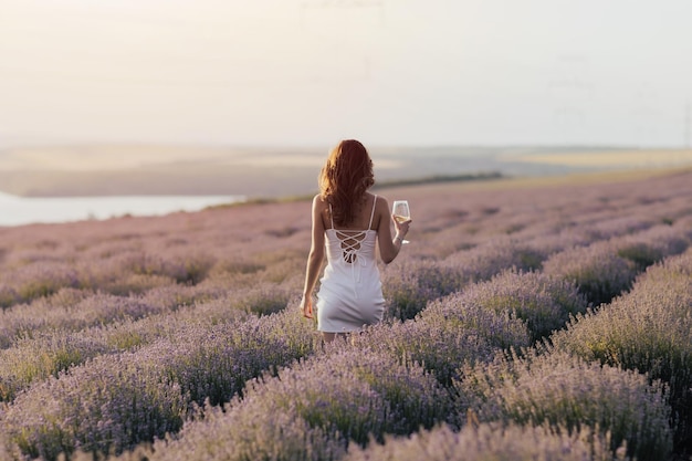 Mulher em um campo de lavanda com uma taça de vinho