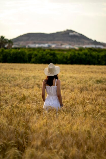 Foto mulher em um campo de trigo olhando para a montanha