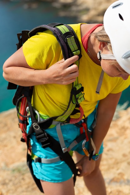 Mulher em um capacete protetor verifica equipamentos e seguros antes de pular de um penhasco