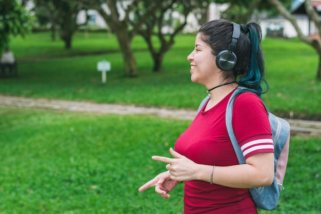 mulher em um parque ouvindo música, cantando e dançando enquanto ela move as mãos