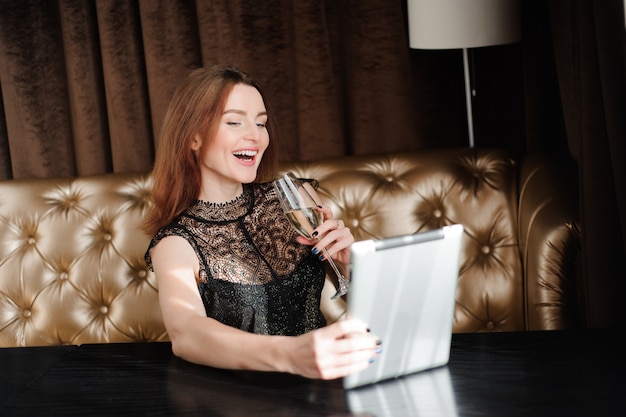 Mulher em um restaurante relaxante com Taça de champanhe e tablet pc.