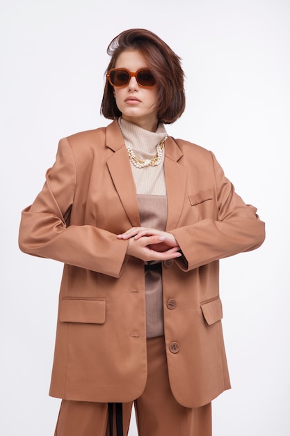 Mulher em um terno bege marrom espartilho óculos de sol jaqueta calça em fundo branco Corte de cabelo Bob