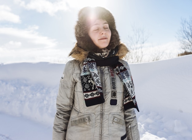 Mulher em um terno de inverno contra o fundo de neve em um dia ensolarado