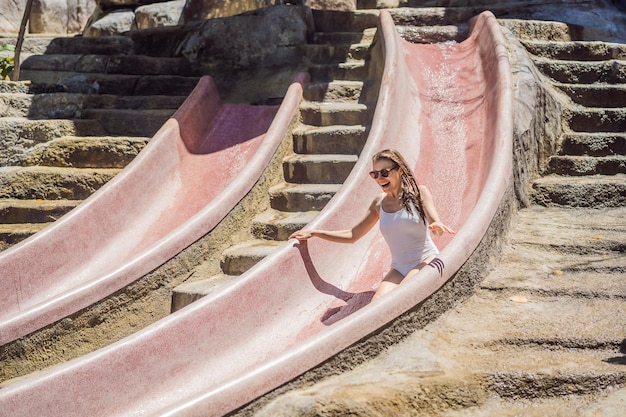 Mulher em um toboágua de pedra em um parque aquático Aqua park Girl desliza para baixo no toboágua