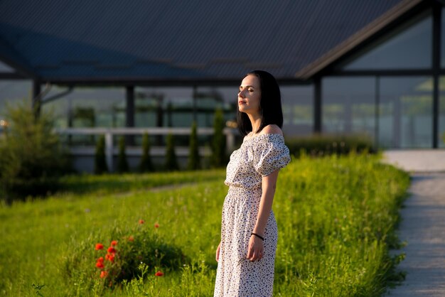 Mulher em um vestido branco em pé em um campo de grama verde