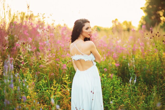 Mulher em um vestido branco, posando em um campo