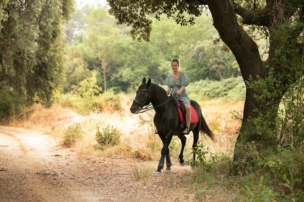 Mulher em um vestido com um cavalo preto na natureza