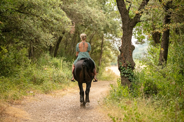 Mulher em um vestido com um cavalo preto na natureza